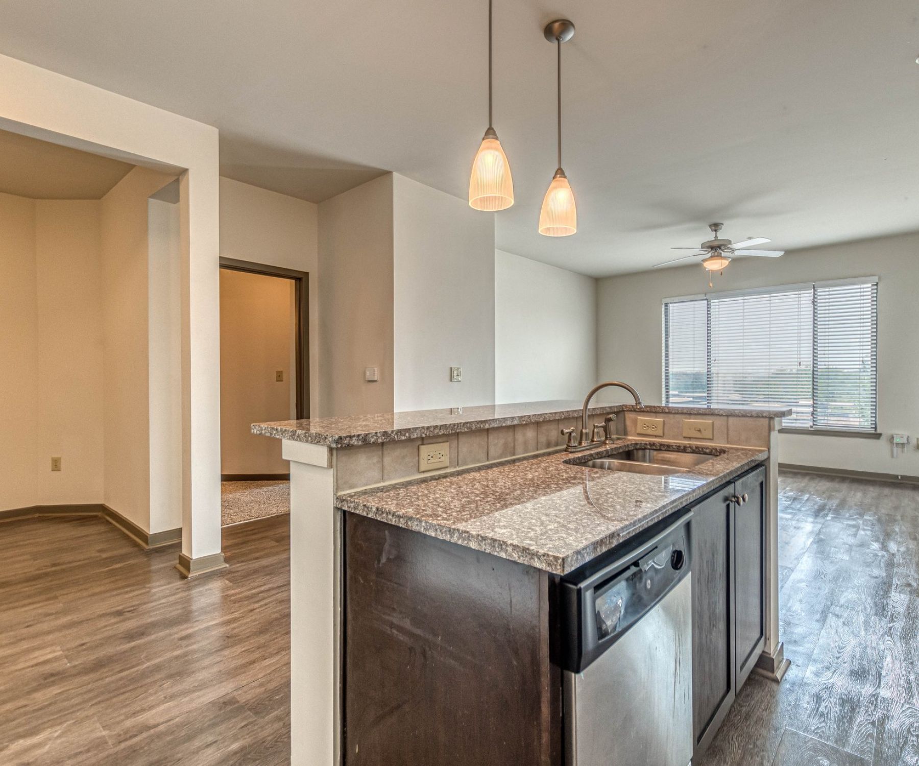 Apex West Midtown modern kitchen with granite countertops, pendant lights, and open living area with large windows and wood floors.
