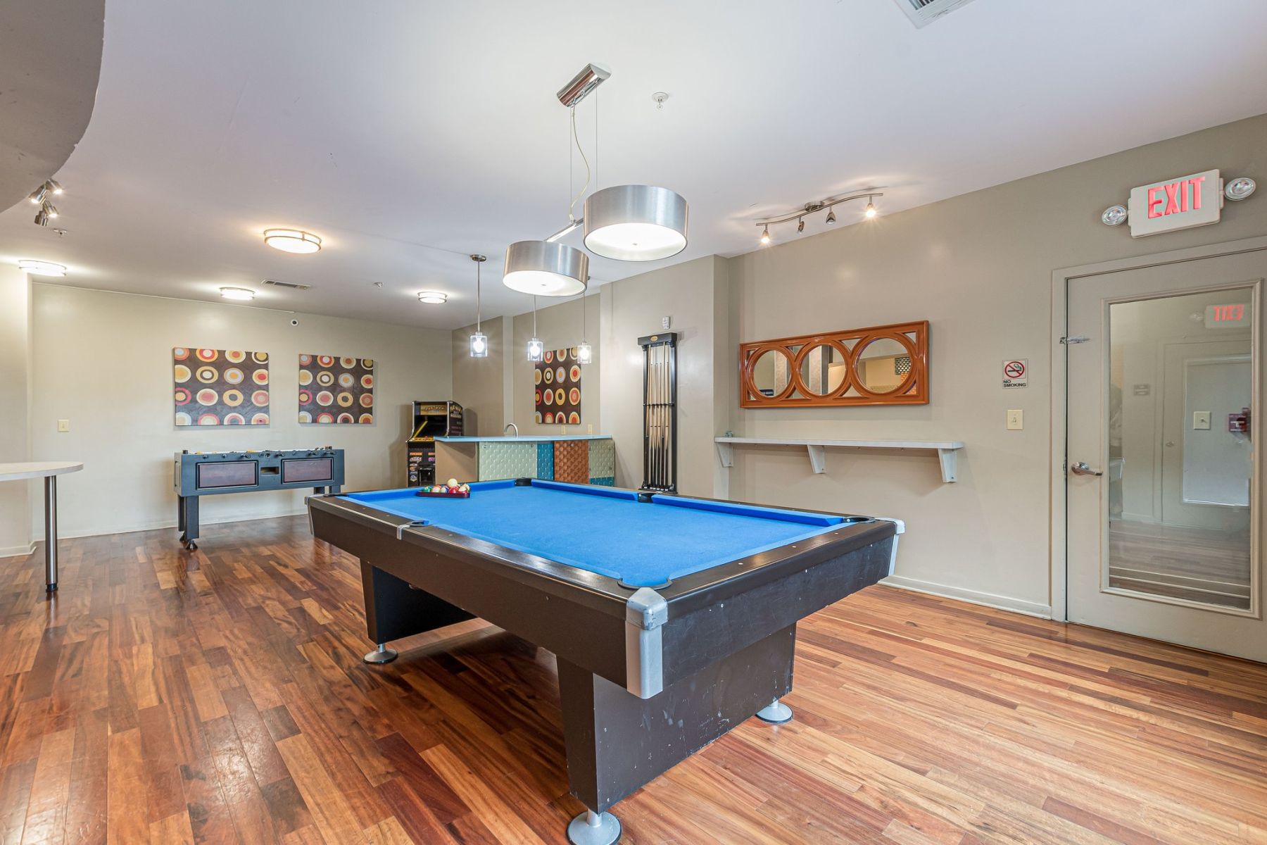 Game room with a blue pool table, foosball table, wood floors, and modern decor on the walls at Apex West Midtown.