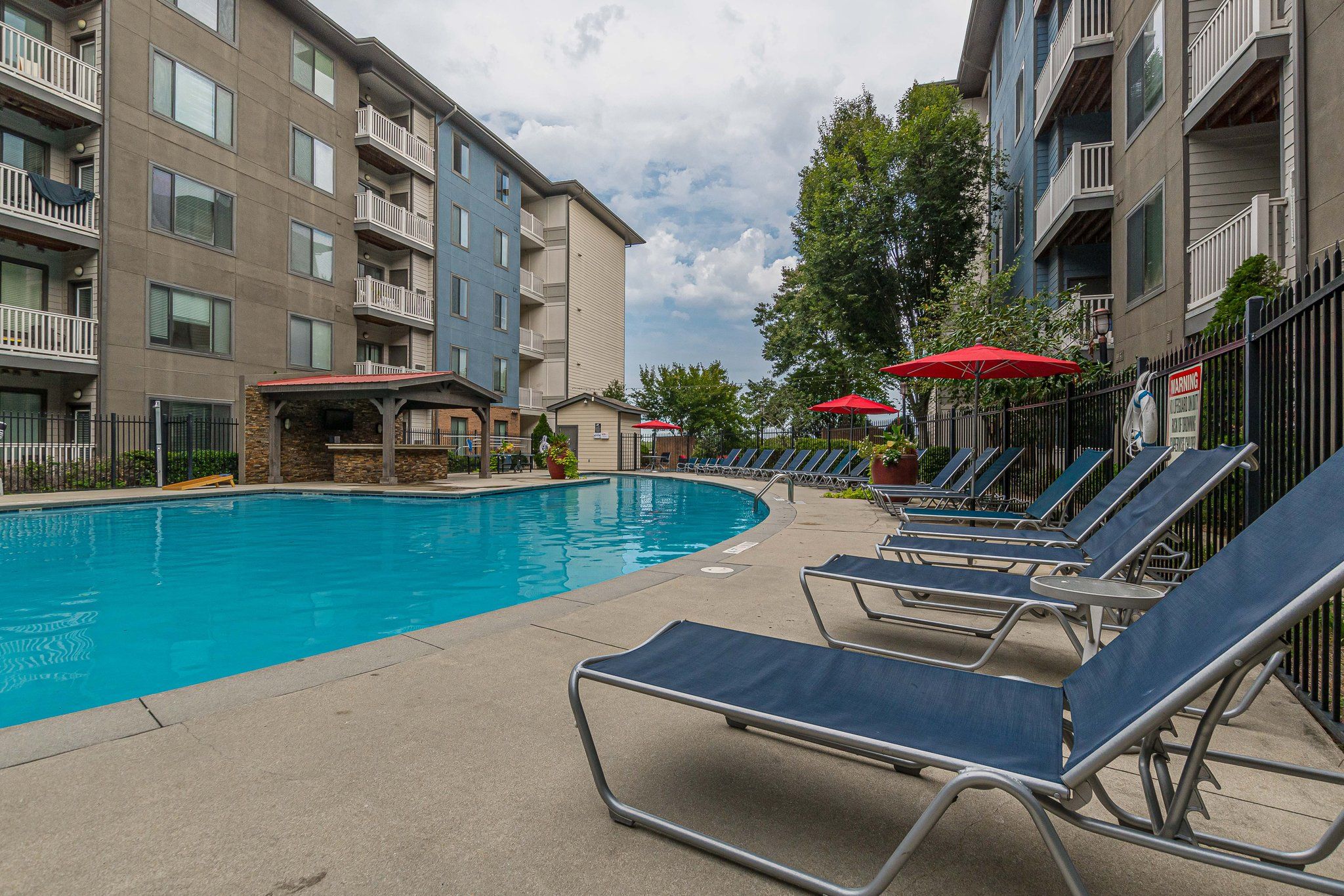 Blue vase with eucalyptus branches on a wooden table in a cozy living room with a sofa and shelves in the background.