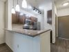 Modern kitchen with granite countertops, stainless steel appliances, and pendant lighting near an entrance door at Apex West Midtown.