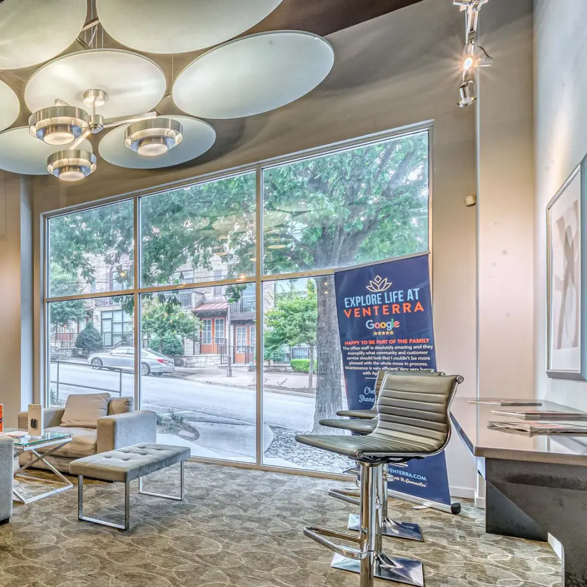 Apex West Midtown lounge with gray sofas, large windows, high ceilings, and contemporary lighting fixtures.