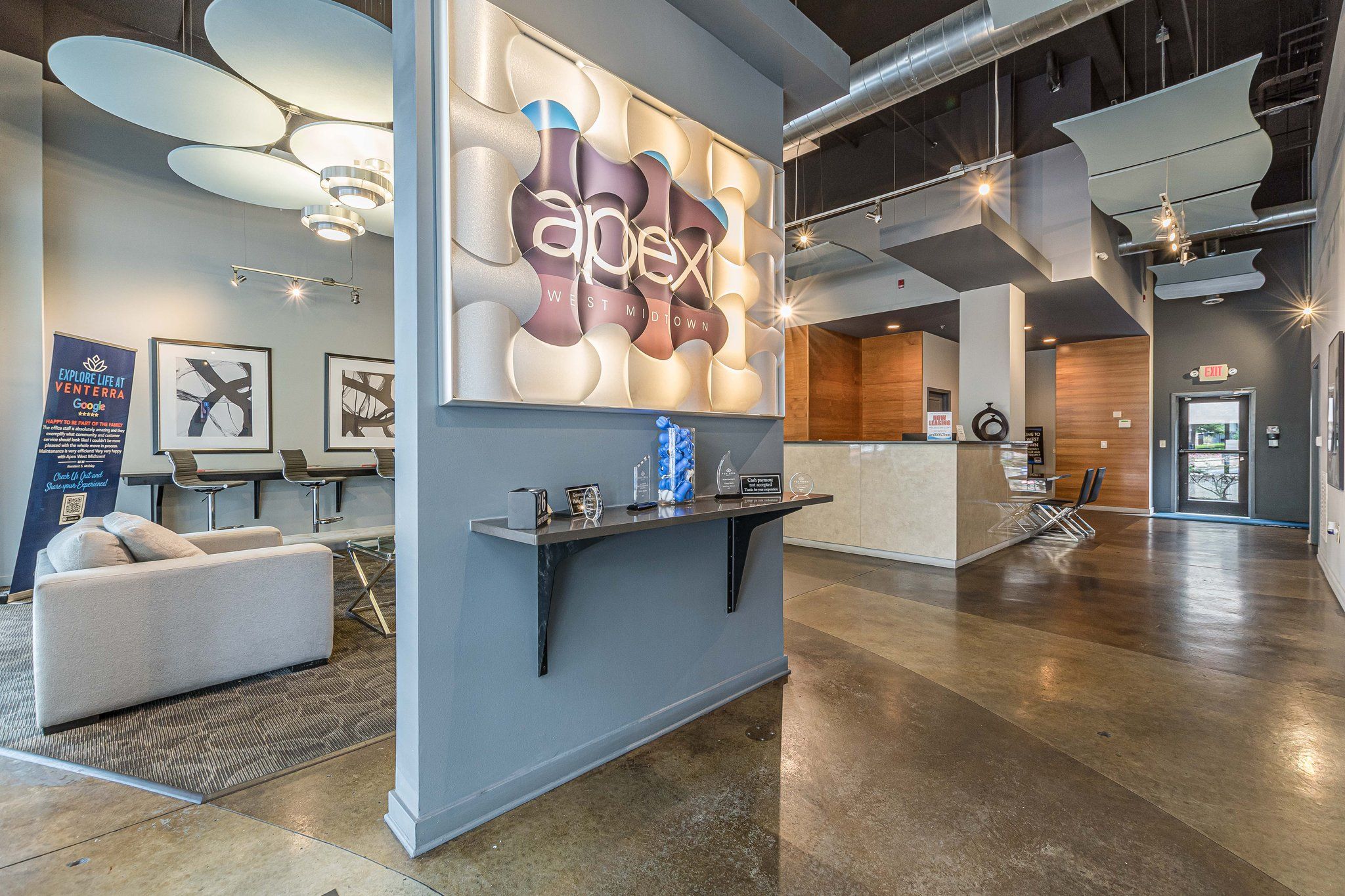 Apex West Midtown office lobby with stylish decor, "apex" sign on wall, seating area, and reception desk in background.
