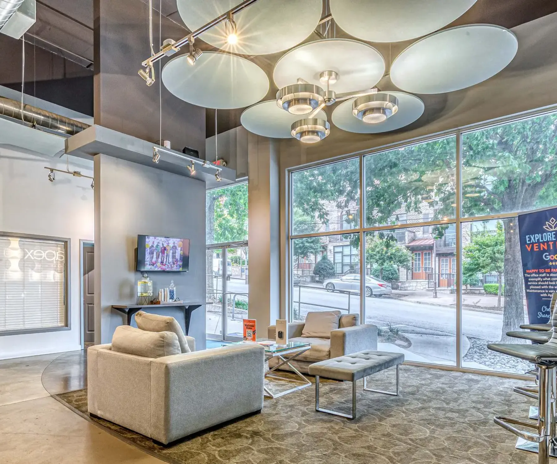Apex West Midtown lounge with gray sofas, large windows, high ceilings, and contemporary lighting fixtures.